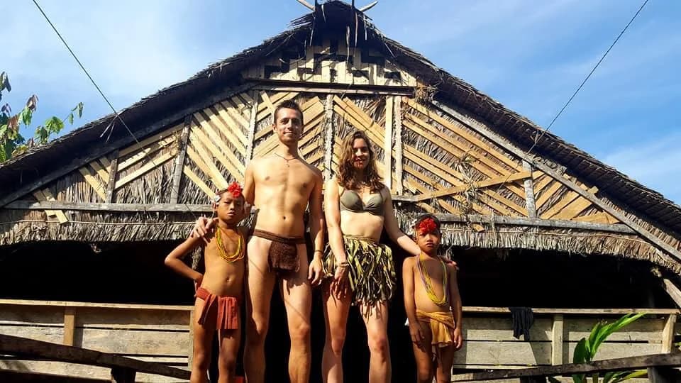 Guests and Mentawai hosts in front of an Uma longhouse